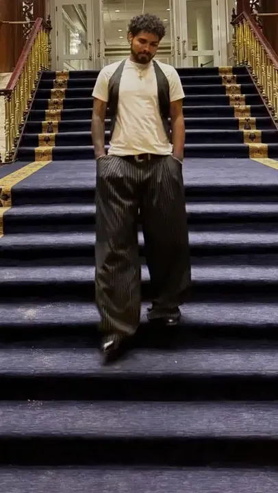Yoru bajando una escalera con alfombra azul y barandas doradas
